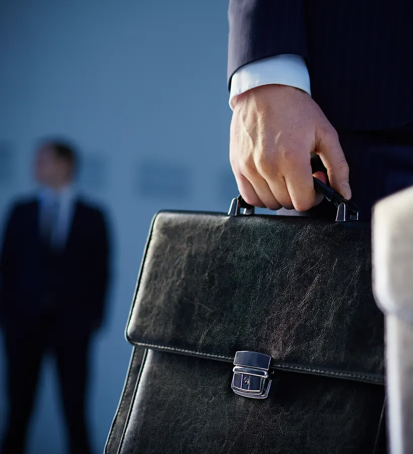 Abogado de traje con portafolio de piel en la mano, listo para salir a una gestión